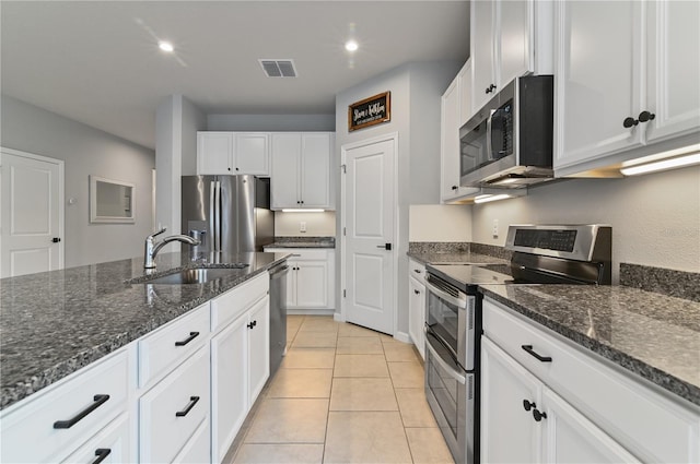 410 Winter Bliss Ln, Mount Dora, FL 32757 - kitchen featuring appliances with stainless steel finishes, white cabinets, dark stone countertops, light tile patterned floors, and recessed lighting
