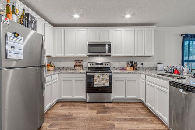 13 Ryken Ln, Palm Coast, FL 32164 - kitchen with stainless steel appliances, a textured ceiling, white cabinets, light wood-type flooring, and recessed lighting