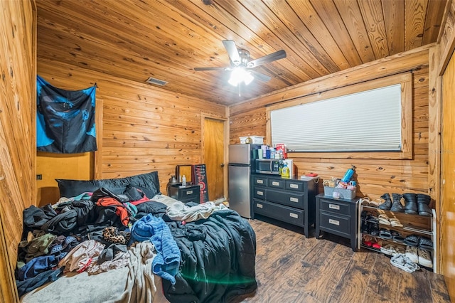 2005 SW Driftwood St, Port St Lucie, FL 34953 - bedroom with freestanding refrigerator, wood ceiling, wood finished floors, wooden walls, and a ceiling fan