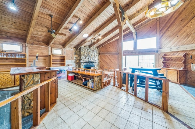 2005 SW Driftwood St, Port St Lucie, FL 34953 - kitchen featuring wooden ceiling, wooden walls, track lighting, a stone fireplace, and a ceiling fan