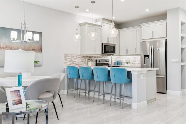 10009 Randal Walk St, Orlando, FL 32832 - kitchen featuring appliances with stainless steel finishes, a peninsula, tasteful backsplash, a kitchen breakfast bar, and a chandelier