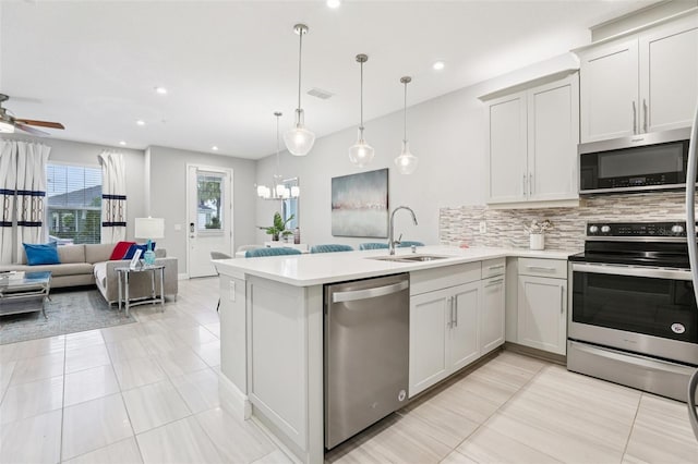 10009 Randal Walk St, Orlando, FL 32832 - kitchen featuring appliances with stainless steel finishes, a peninsula, light countertops, decorative backsplash, and open floor plan