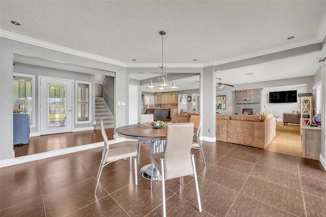 7801 Georgeann St, Winter Park, FL 32792 - dining space featuring a fireplace, dark tile patterned floors, stairs, ornamental molding, and a ceiling fan