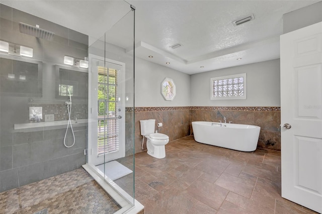 7801 Georgeann St, Winter Park, FL 32792 - bathroom featuring tile walls, tiled shower, a wainscoted wall, a freestanding bath, and a textured ceiling