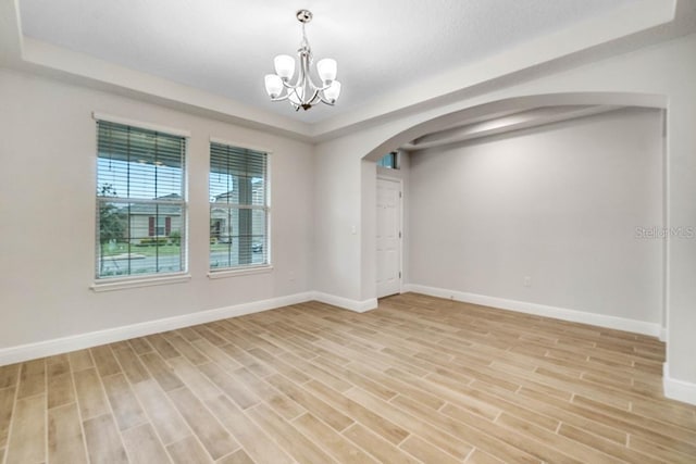 16146 Point Rock Dr, Winter Garden, FL 34787 - spare room with arched walkways, a chandelier, light wood-style floors, and a tray ceiling