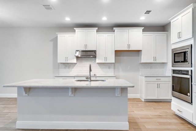 16146 Point Rock Dr, Winter Garden, FL 34787 - kitchen with appliances with stainless steel finishes, ventilation hood, white cabinets, and recessed lighting
