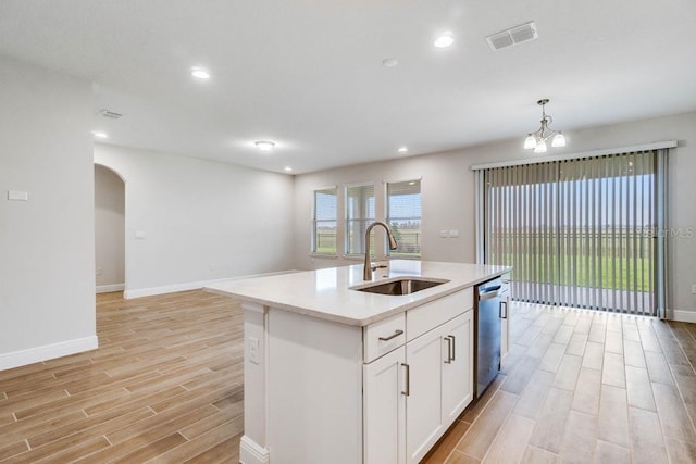16146 Point Rock Dr, Winter Garden, FL 34787 - kitchen with stainless steel dishwasher, light wood-style flooring, light countertops, arched walkways, and white cabinetry