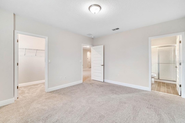 16146 Point Rock Dr, Winter Garden, FL 34787 - unfurnished bedroom with carpet floors, a walk in closet, a textured ceiling, a closet, and ensuite bath