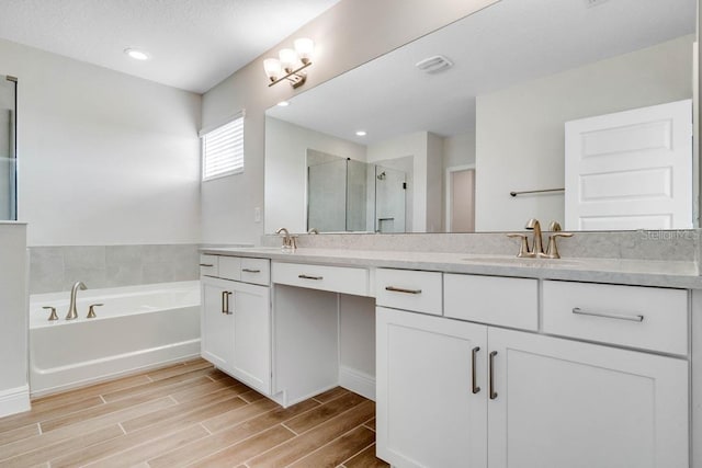 16146 Point Rock Dr, Winter Garden, FL 34787 - bathroom with double vanity, a stall shower, wood finished floors, and a garden tub