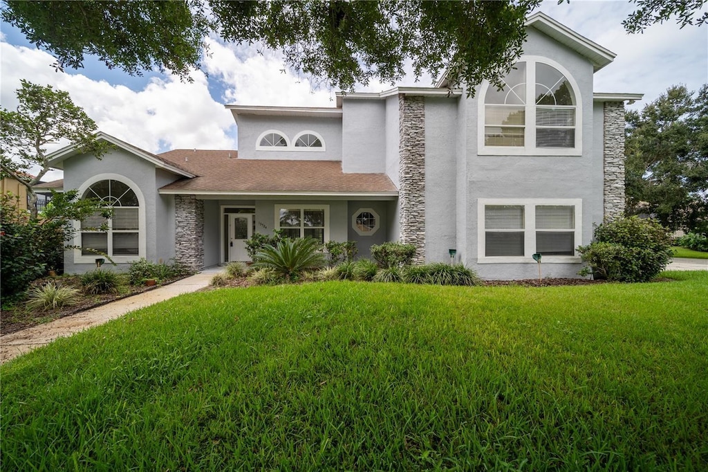 13524 Lake Luntz Dr, Winter Garden, FL 34787 - view of front of house featuring stucco siding, a front lawn, stone siding, and roof with shingles