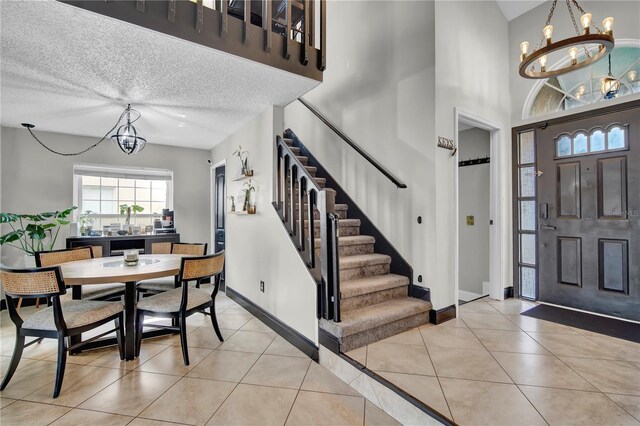 2235 Meadowmouse St, Orlando, FL 32837 - entrance foyer with a chandelier, stairs, light tile patterned flooring, a towering ceiling, and a textured ceiling