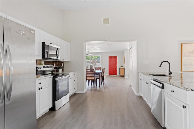 370 Hand Ave, Ormond Beach, FL 32174 - kitchen featuring stainless steel appliances, light wood finished floors, light stone counters, white cabinets, and tasteful backsplash