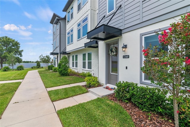 12468 Koshiba Aly, Orlando, FL 32827 - view of exterior entry featuring a yard, a water view, and brick siding