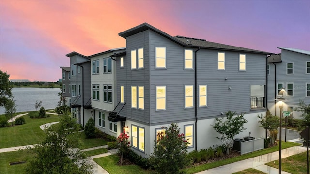 12468 Koshiba Aly, Orlando, FL 32827 - property exterior at dusk featuring a water view, stucco siding, and a lawn