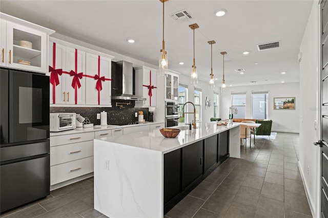 12468 Koshiba Aly, Orlando, FL 32827 - kitchen featuring fridge, wall chimney exhaust hood, light countertops, backsplash, and a kitchen island with sink