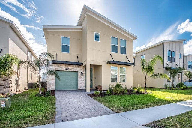 8982 Cabot Cliffs Dr, Davenport, FL 33896 - view of front of property featuring stucco siding, a garage, a front yard, decorative driveway, and stone siding
