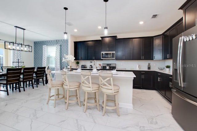 8982 Cabot Cliffs Dr, Davenport, FL 33896 - kitchen with stainless steel appliances, light marble finish floors, light countertops, a breakfast bar area, and recessed lighting