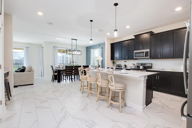 8982 Cabot Cliffs Dr, Davenport, FL 33896 - kitchen featuring stainless steel appliances, recessed lighting, light countertops, a breakfast bar, and an island with sink