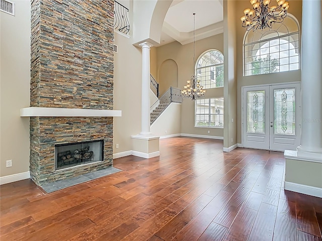 2209 Callaway Ct, Davenport, FL 33837 - unfurnished living room with a chandelier, a high ceiling, hardwood / wood-style flooring, decorative columns, and a fireplace
