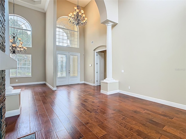 2209 Callaway Ct, Davenport, FL 33837 - foyer featuring a chandelier, decorative columns, arched walkways, a towering ceiling, and dark wood-style flooring