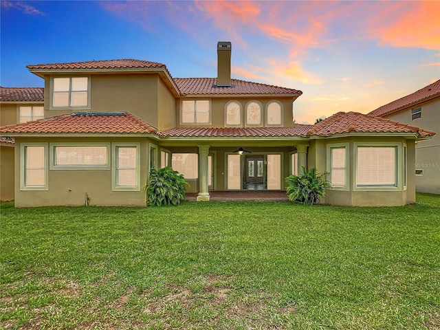 2209 Callaway Ct, Davenport, FL 33837 - rear view of house featuring a chimney, a tiled roof, a lawn, and stucco siding