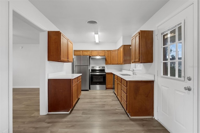 203 E Lakeview Ave, Eustis, FL 32726 - kitchen with stainless steel appliances, under cabinet range hood, brown cabinetry, light wood-style flooring, and light countertops