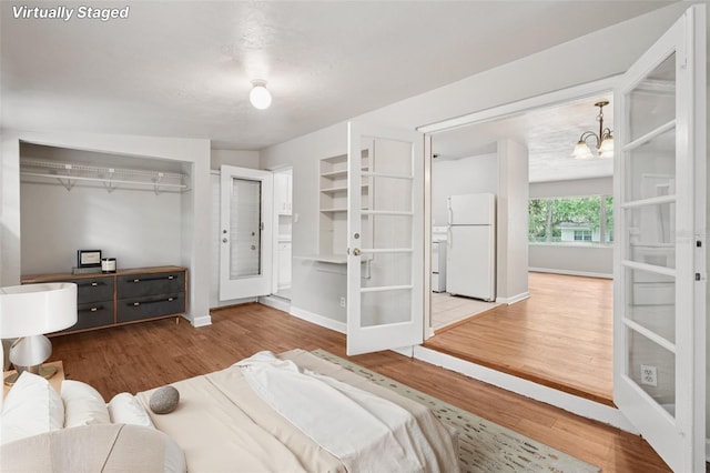 518 NW 36th Ter, Gainesville, FL 32607 - bedroom featuring freestanding refrigerator, french doors, wood finished floors, a chandelier, and a closet