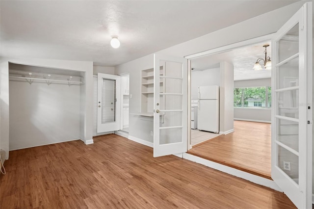 518 NW 36th Ter, Gainesville, FL 32607 - unfurnished bedroom featuring freestanding refrigerator, french doors, wood finished floors, and a chandelier