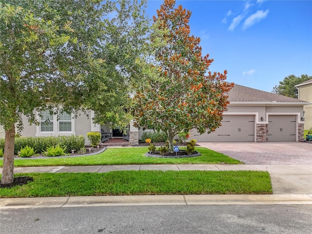31980 Geoff Way, Sorrento, FL 32776 - view of property hidden behind natural elements featuring stone siding, decorative driveway, stucco siding, an attached garage, and a front lawn