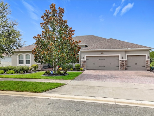 31980 Geoff Way, Sorrento, FL 32776 - view of front of home featuring stucco siding, stone siding, decorative driveway, a garage, and roof with shingles