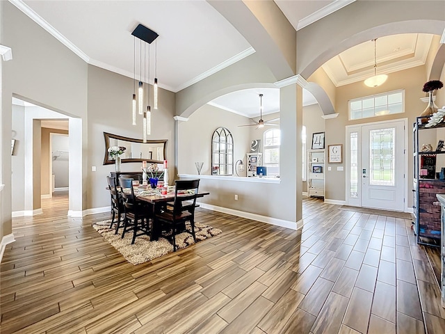 31980 Geoff Way, Sorrento, FL 32776 - dining area with arched walkways, a high ceiling, wood finished floors, ceiling fan, and crown molding