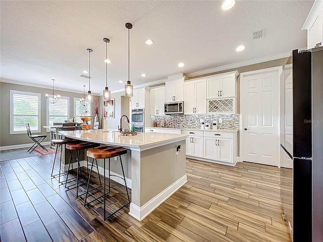 31980 Geoff Way, Sorrento, FL 32776 - kitchen featuring stainless steel appliances, ornamental molding, light countertops, white cabinets, and wood finish floors