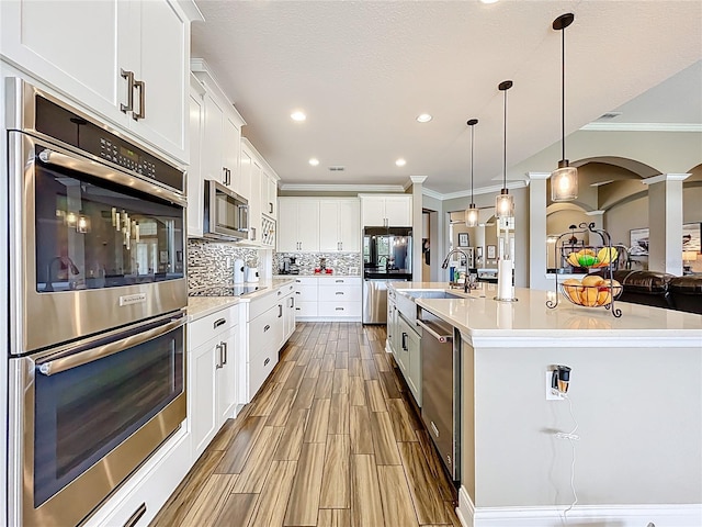 31980 Geoff Way, Sorrento, FL 32776 - kitchen featuring appliances with stainless steel finishes, ornamental molding, arched walkways, decorative backsplash, and white cabinetry