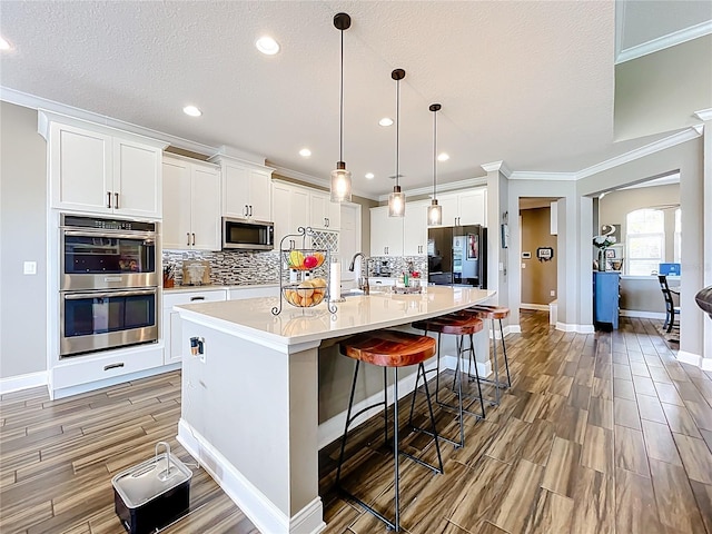 31980 Geoff Way, Sorrento, FL 32776 - kitchen with stainless steel appliances, crown molding, wood tiled floors, tasteful backsplash, and white cabinetry