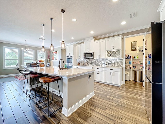 31980 Geoff Way, Sorrento, FL 32776 - kitchen featuring appliances with stainless steel finishes, crown molding, light countertops, tasteful backsplash, and white cabinets