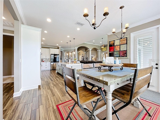 31980 Geoff Way, Sorrento, FL 32776 - dining space featuring a chandelier, arched walkways, crown molding, recessed lighting, and wood tiled floors