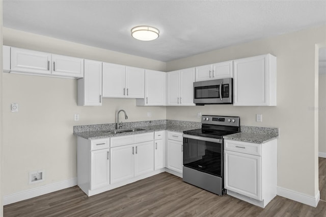 7612 Pomelo Dr, Orlando, FL 32819 - kitchen with appliances with stainless steel finishes, wood finished floors, white cabinetry, and light stone countertops