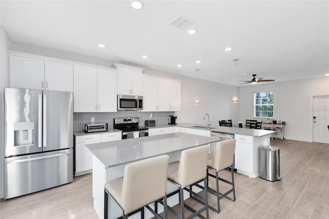 3099 Ella Way, Saint Cloud, FL 34771 - kitchen featuring appliances with stainless steel finishes, a peninsula, a ceiling fan, light wood-type flooring, and recessed lighting
