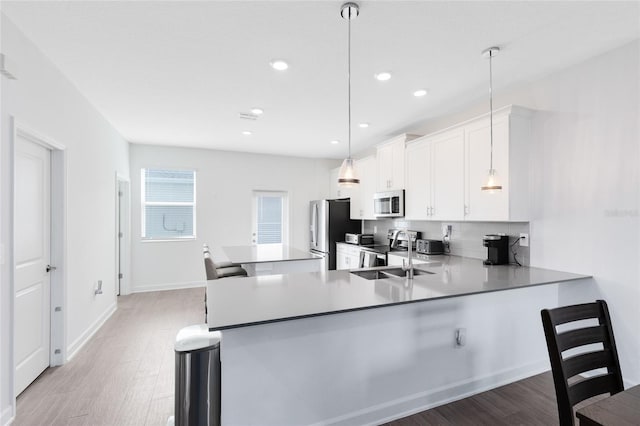 3099 Ella Way, Saint Cloud, FL 34771 - kitchen with stainless steel appliances, light wood finished floors, white cabinets, a kitchen bar, and backsplash