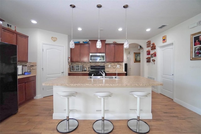 1588 Diamond Loop Dr, Kissimmee, FL 34744 - kitchen featuring stainless steel microwave, black refrigerator, tasteful backsplash, light wood finished floors, and range