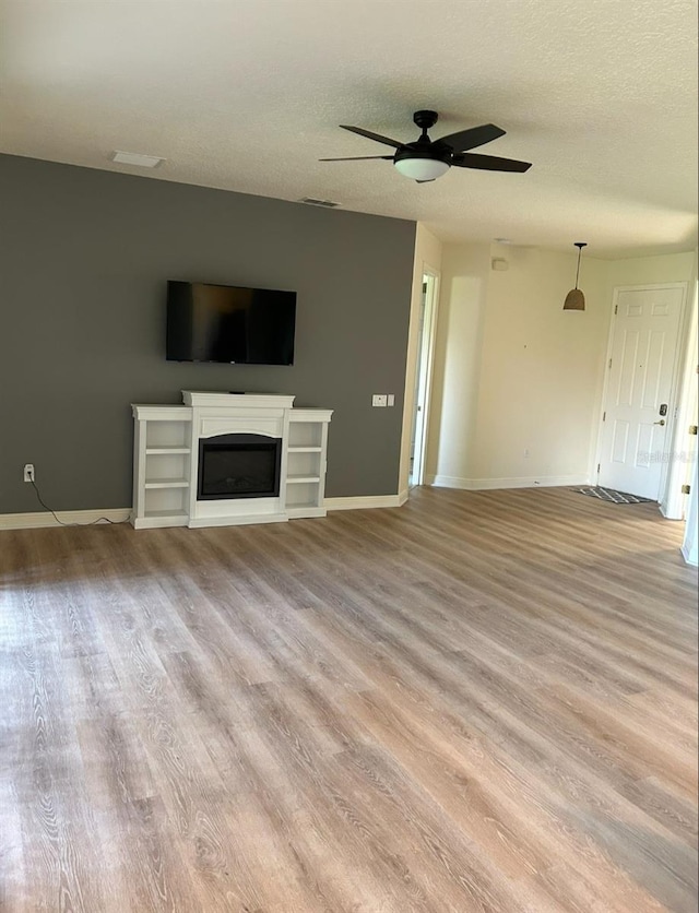 152 Glendale Ct, Kissimmee, FL 34759 - unfurnished living room with light wood-style floors, a ceiling fan, a textured ceiling, and a glass covered fireplace
