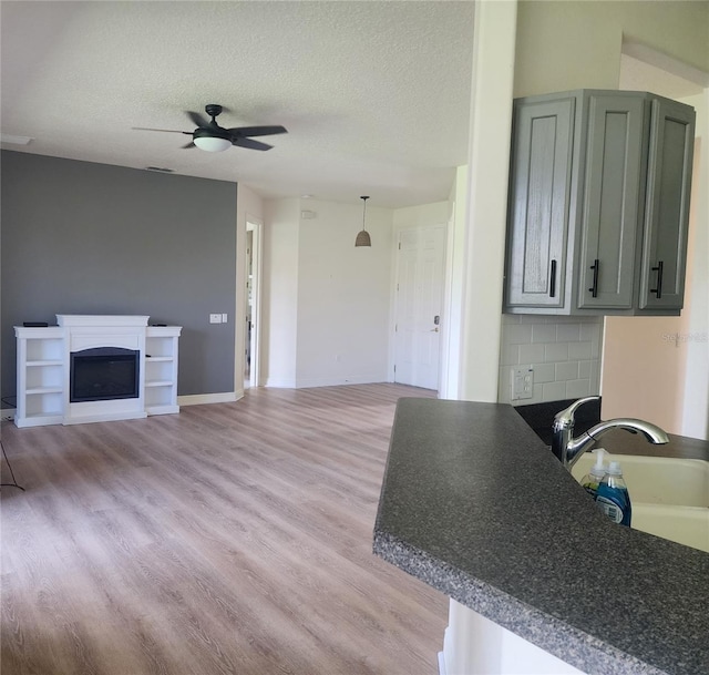 152 Glendale Ct, Kissimmee, FL 34759 - kitchen with ceiling fan, light wood-style flooring, a fireplace, open floor plan, and dark countertops