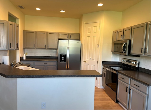 152 Glendale Ct, Kissimmee, FL 34759 - kitchen with appliances with stainless steel finishes, dark countertops, a peninsula, decorative backsplash, and recessed lighting