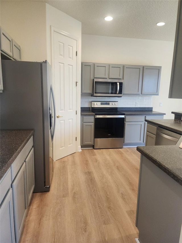 152 Glendale Ct, Kissimmee, FL 34759 - kitchen with stainless steel appliances, dark countertops, light wood-style flooring, backsplash, and gray cabinets