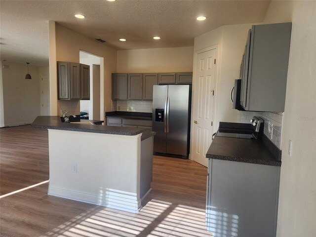 152 Glendale Ct, Kissimmee, FL 34759 - kitchen with stainless steel refrigerator with ice dispenser, stove, dark countertops, wood finished floors, and backsplash