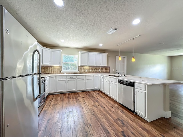 117 Burns Ave, Longwood, FL 32750 - kitchen featuring stainless steel appliances, a peninsula, dark wood finished floors, decorative backsplash, and a textured ceiling