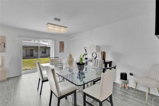 205 Cimarron Dr, Kissimmee, FL 34759 - dining room with a chandelier, light wood-style flooring, and a textured ceiling