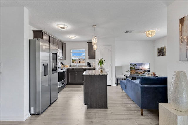 205 Cimarron Dr, Kissimmee, FL 34759 - kitchen with appliances with stainless steel finishes, open floor plan, a kitchen island, light wood-style floors, and dark brown cabinetry