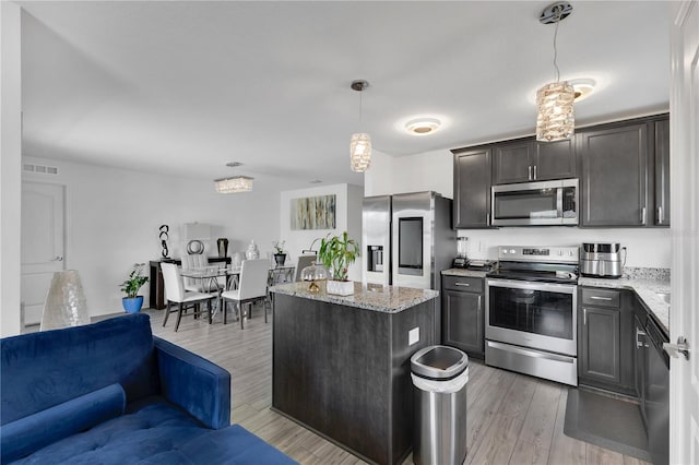 205 Cimarron Dr, Kissimmee, FL 34759 - kitchen with stainless steel appliances, light stone countertops, open floor plan, light wood finished floors, and a center island