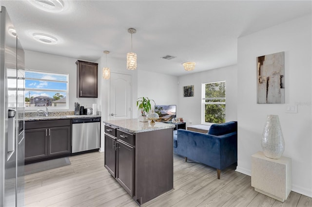 205 Cimarron Dr, Kissimmee, FL 34759 - kitchen with appliances with stainless steel finishes, dark brown cabinets, light stone countertops, open floor plan, and light wood-style flooring